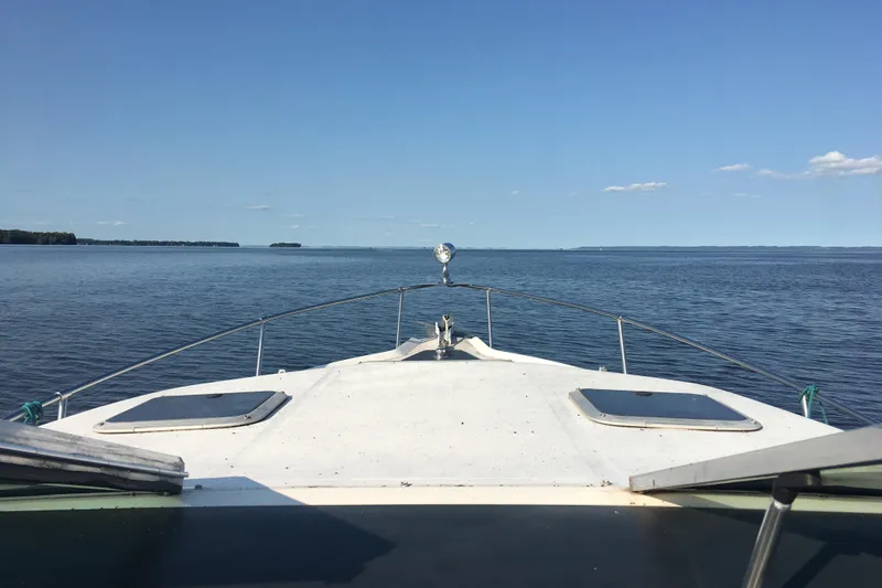 Slide: The Image of 1993 Sea Ray 250 Sundancer cruising on a calm lake under a clear blue sky. - 4