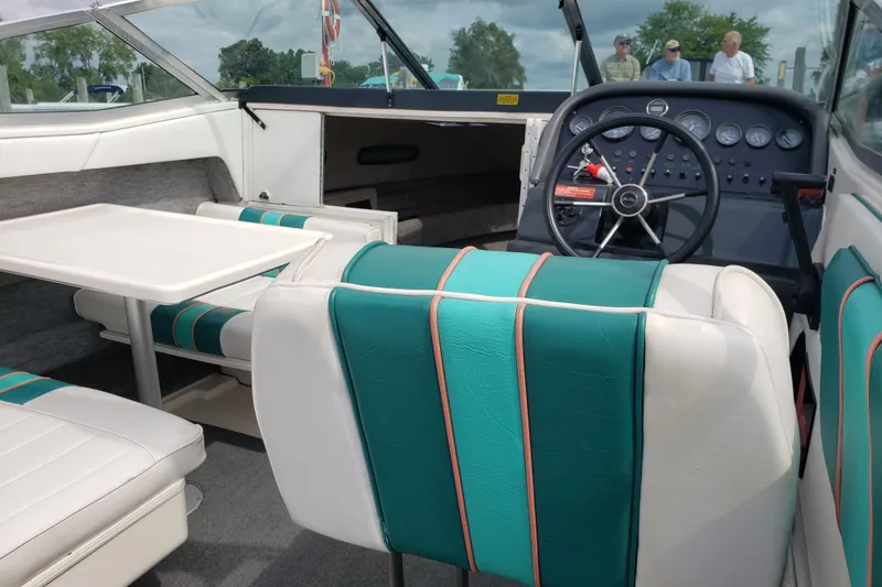 Slide: The Image of 1993 Searay 250EC boat interior with teal and white seating, steering wheel, and table. - 8