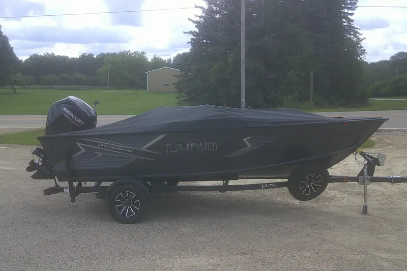 Slide: The Image of 2026 Lund 1675 Adventure SS boat on trailer, covered, with Mercury outboard motor. - 14