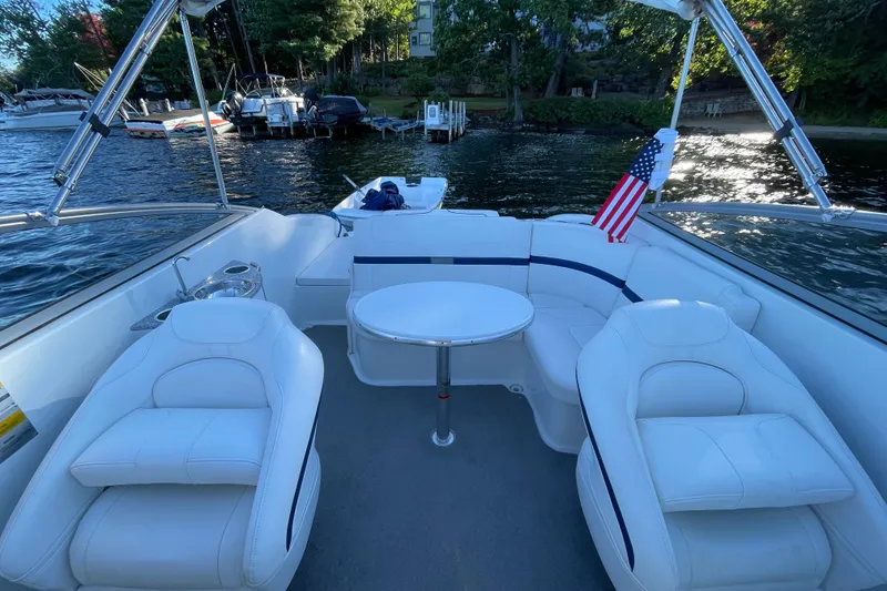 Slide: The Image of 2005 Formula 240 Bowrider boat interior with white seating and American flag on a lake. - 16