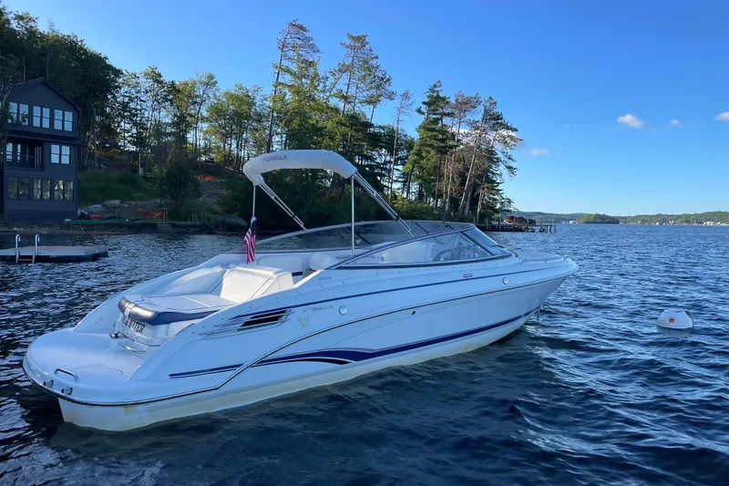 Slide: The Image of 2005 Formula 240 Bowrider boat on a serene lake with trees in the background. - 2
