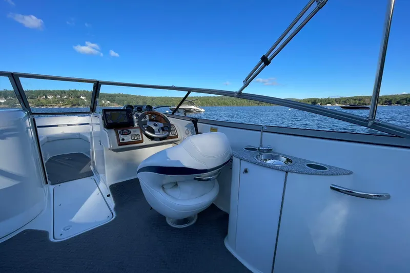 Slide: The Image of 2005 Formula 240 Bowrider boat interior with steering wheel and sink, on a scenic lake. - 6