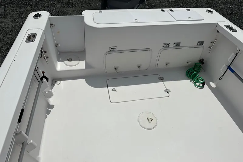 Slide: The Image of 2003 PROLINE Sport Center Console boat deck with storage compartments and coiled green hose. - 16