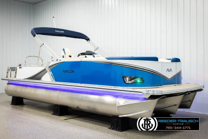 Slide: The Image of 2026 Avalon LSZ VRB pontoon boat with blue accents in a showroom. - 2