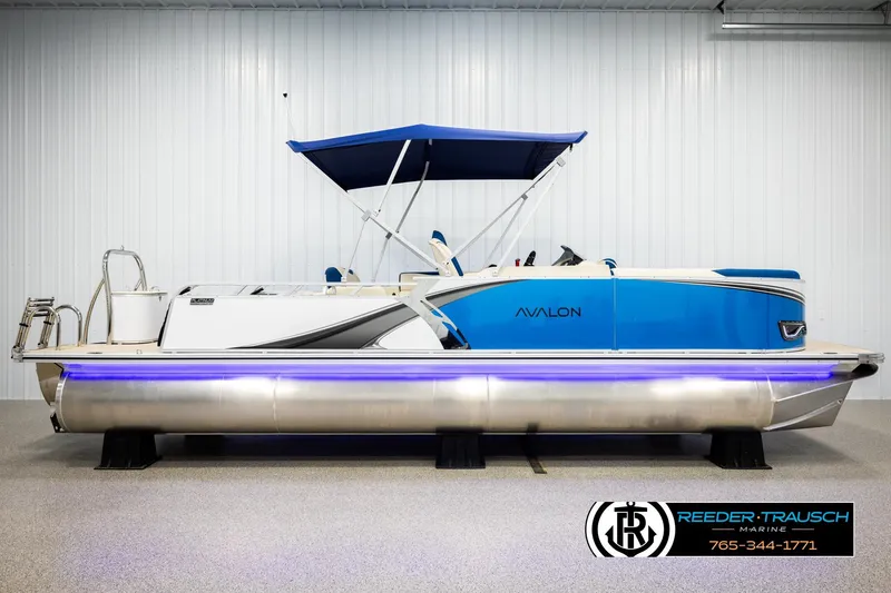 Slide: The Image of 2026 Avalon LSZ VRB pontoon boat with blue canopy and sleek design in showroom. - 5