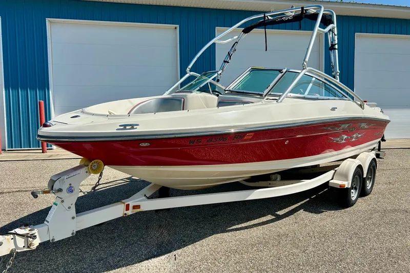 Slide: The Image of 2008 Searay 205 SPORT boat on trailer, red and white, parked near blue building. - 19