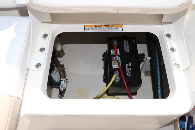 Slide: The Image of 2019 Robalo R207 Dual Console boat battery compartment with wiring and warning label. - 12