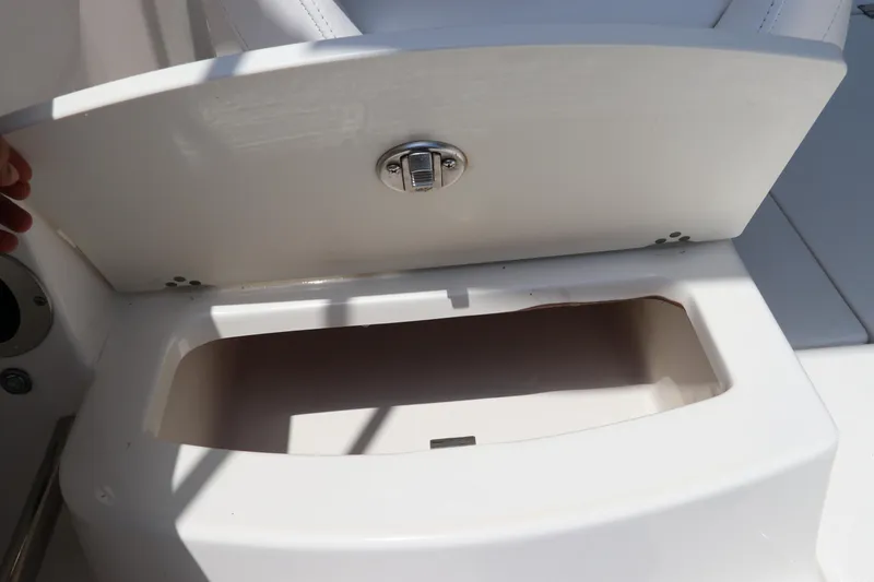 Slide: The Image of 2019 Robalo R207 Dual Console storage compartment with open lid, showcasing interior space. - 16