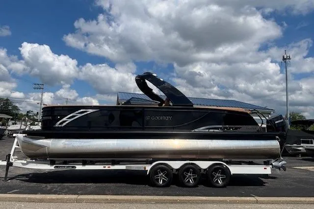 Slide: The Image of 2025 Godfrey San Pan SP2700SBW pontoon boat on trailer under cloudy sky. - 6