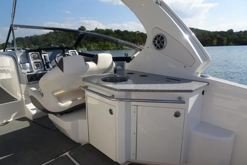 Slide: The Image of 2015 Chaparral 327 SSX boat interior with helm and kitchenette by the lake. - 10