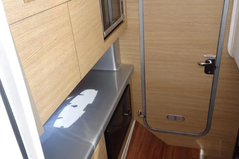 Slide: The Image of 2015 Chaparral 327 SSX interior with modern wood finish and compact kitchenette. - 18