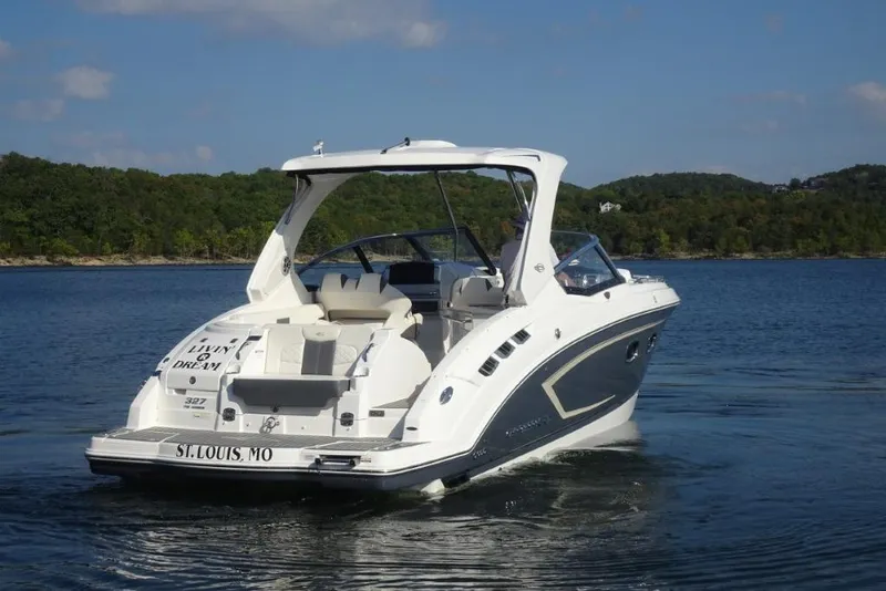Slide: The Image of 2015 Chaparral 327 SSX boat cruising on a serene lake with lush green shoreline. - 3