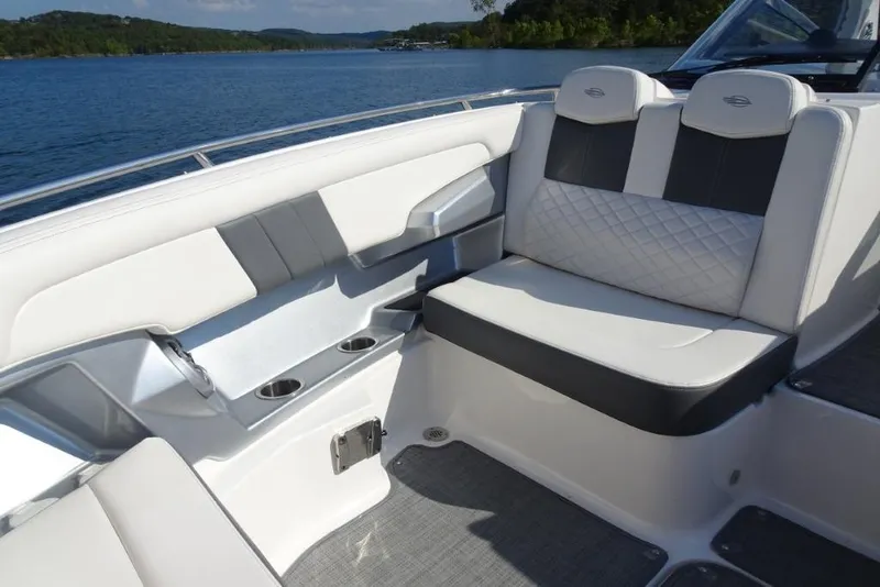 Slide: The Image of 2015 Chaparral 327 SSX boat interior with cushioned seating and cup holders on a sunny day. - 31