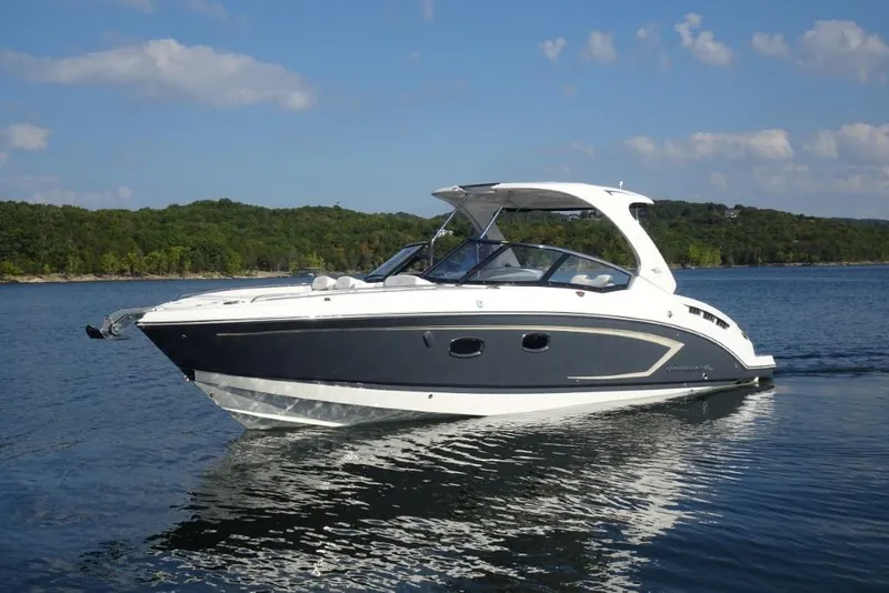 Slide: The Image of 2015 Chaparral 327 SSX boat cruising on a serene lake under a clear sky. - 6