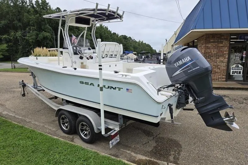 Slide: The Image of 2007 Sea Hunt Triton 220 boat on trailer with Yamaha outboard motor, parked near a store. - 2
