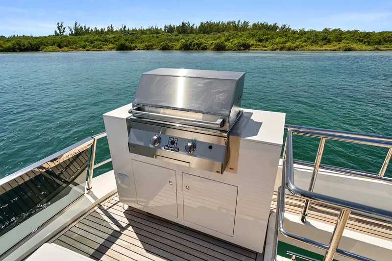 Slide: The Image of Outdoor grill on 2023 Astondoa 66 Flybridge yacht, overlooking serene water and lush greenery. - 11