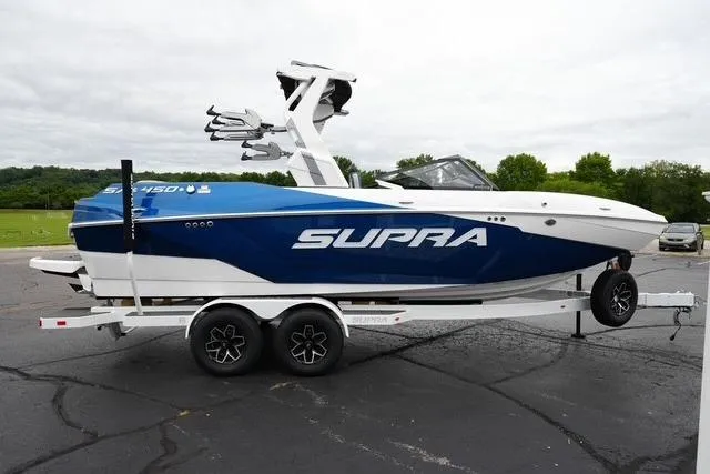 Slide: The Image of 2026 Supra SA boat on trailer, blue and white design, parked outdoors. - 4