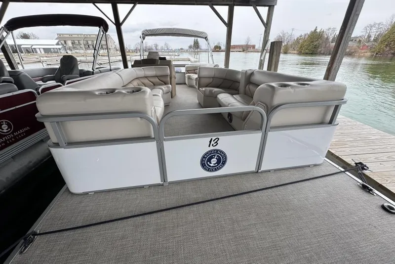 Slide: The Image of 2007 Manitou Aurora boat interior with beige seating and motor, parked on gravel. - 11