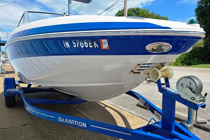 Slide: The Image of 2013 Glastron GLS 195 BR boat on trailer, blue and white design, parked outdoors. - 12