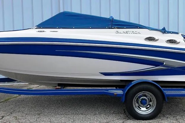 Slide: The Image of 2013 Glastron GLS 195 BR boat with blue and white design on trailer. - 13