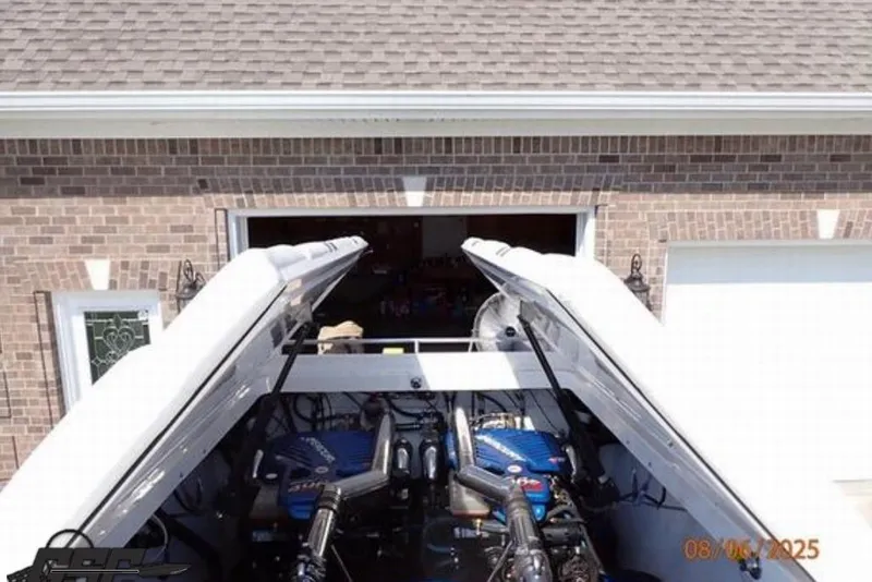 Slide: The Image of 2006 Fountain 47 Lightning boat engine compartment with open hatches, parked in front of a garage. - 46
