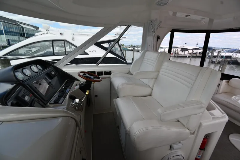 Slide: The Image of 2005 Sea Ray 390 Motor Yacht helm with white seating and control panel, docked at marina. - 16