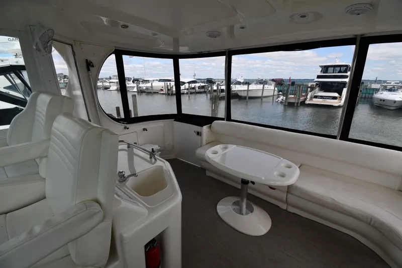 Slide: The Image of 2005 Sea Ray 390 Motor Yacht interior with white seating, table, and marina view. - 20
