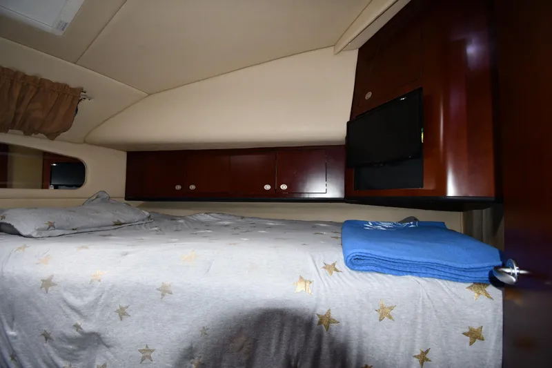 Slide: The Image of 2005 Sea Ray 390 Motor Yacht bedroom with star-patterned bedding and wooden cabinets. - 28