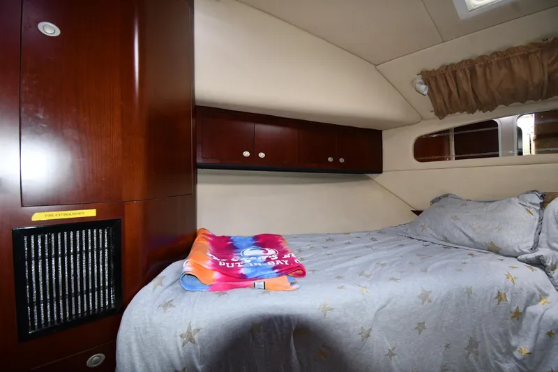 Slide: The Image of 2005 Sea Ray 390 Motor Yacht cabin with bed, wooden cabinets, and star-patterned bedding. - 29