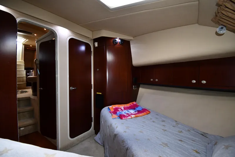 Slide: The Image of 2005 Sea Ray 390 Motor Yacht interior cabin with bed, wooden cabinets, and soft lighting. - 30