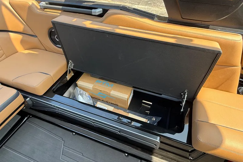 Slide: The Image of 2026 Supra SE 550 boat interior with open storage compartment and tan leather seats. - 13