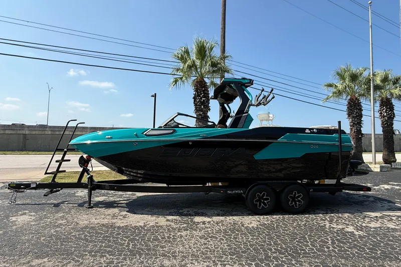 Slide: The Image of 2026 Supra SE 550 boat on trailer, parked near palm trees under clear blue sky. - 3