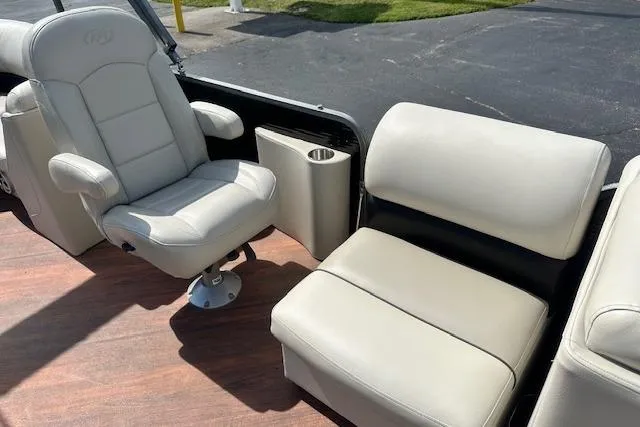 Slide: The Image of 2017 Manitou 23 Oasis boat interior with beige seating and wood flooring. - 17