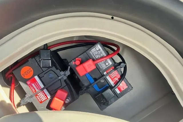 Slide: The Image of Batteries in a 2017 Manitou 23 Oasis boat, secured with red and black cables. - 18