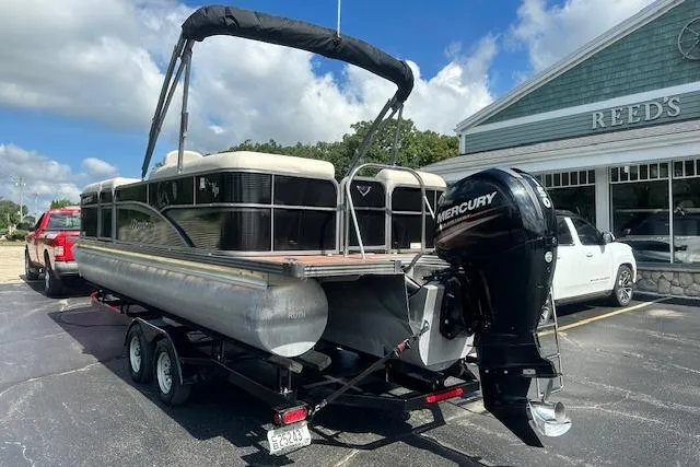 Slide: The Image of 2017 Manitou 23 Oasis pontoon boat with Mercury engine on trailer, parked outside Reed's store. - 2