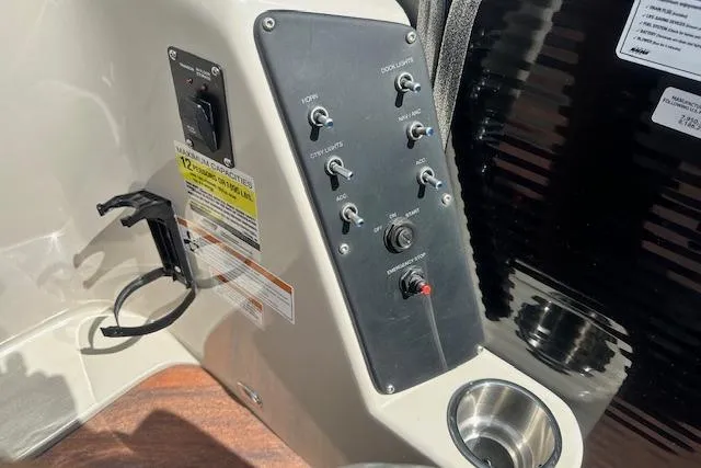 Slide: The Image of Control panel of 2017 Manitou 23 Oasis boat with switches and cup holder. - 23