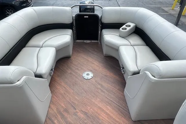 Slide: The Image of 2017 Manitou 23 Oasis boat interior with plush seating and wood-style flooring. - 28