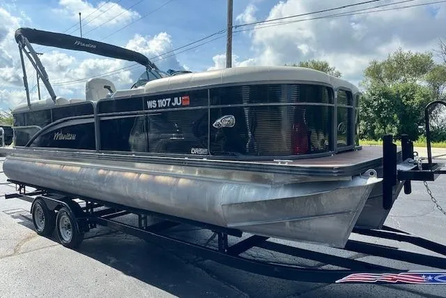 Slide: The Image of 2017 Manitou 23 Oasis pontoon boat on trailer, parked outdoors under a cloudy sky. - 4