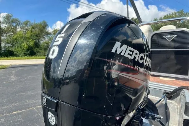 Slide: The Image of 2017 Manitou 23 Oasis with Mercury 150 FourStroke outboard engine, parked outdoors. - 6