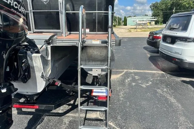 Slide: The Image of 2017 Manitou 23 Oasis boat with ladder and Mercury engine in parking lot. - 7