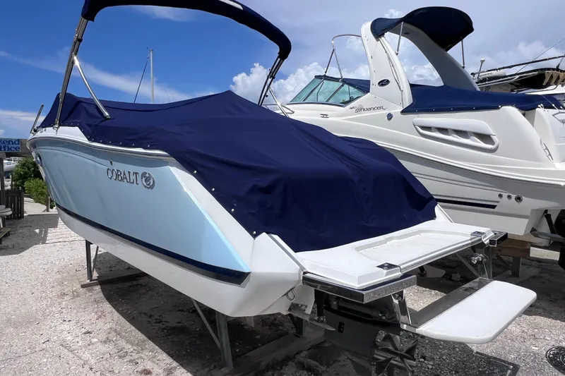 Slide: The Image of 2015 Cobalt 26SD boat with blue cover, docked beside another vessel. - 12