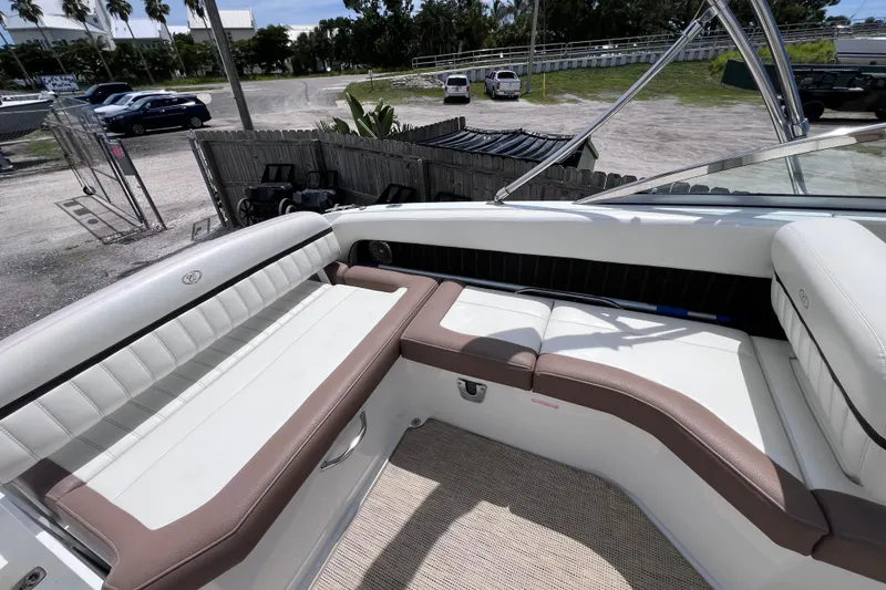 Slide: The Image of 2015 Cobalt 26SD boat interior with white and brown seating, parked outdoors. - 17