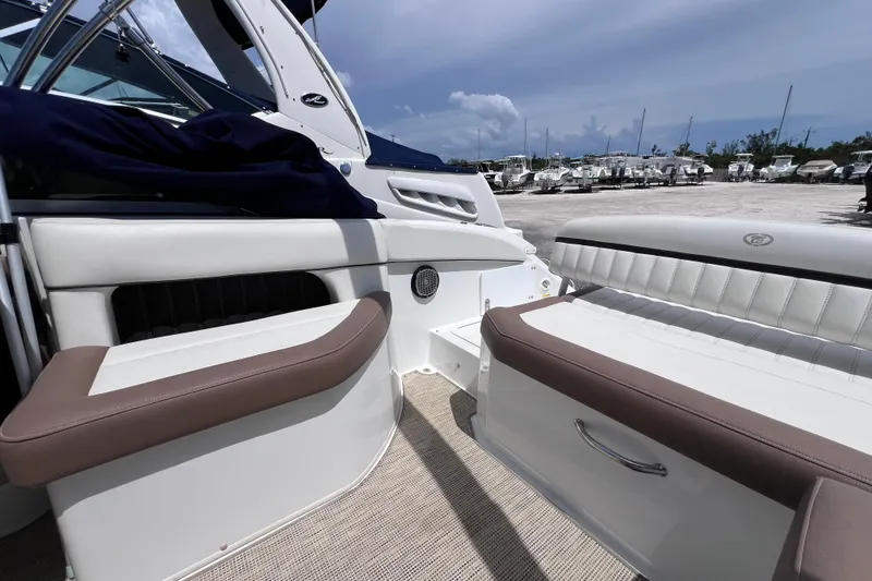 Slide: The Image of 2015 Cobalt 26SD boat interior with white and brown seating, parked outdoors. - 18