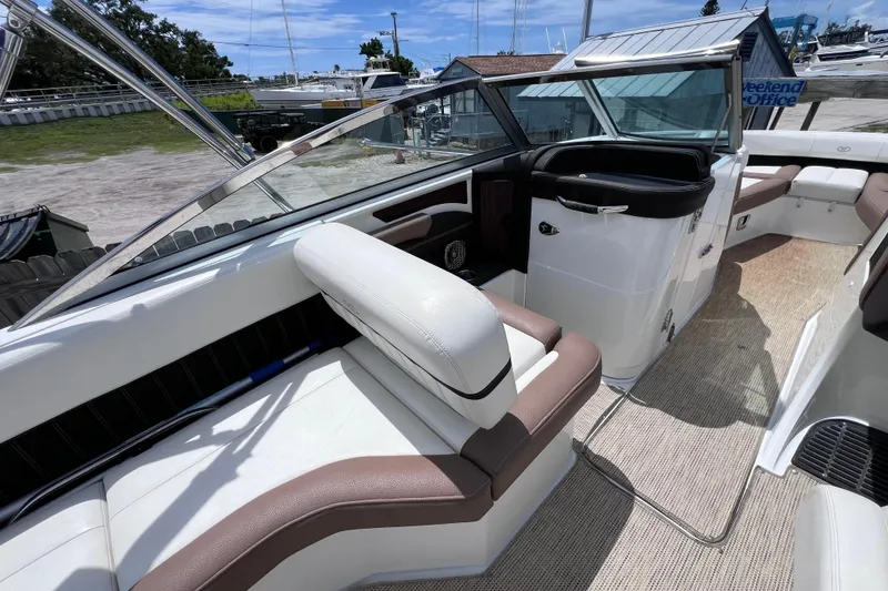 Slide: The Image of 2015 Cobalt 26SD boat interior with white and brown seating, docked at marina. - 21