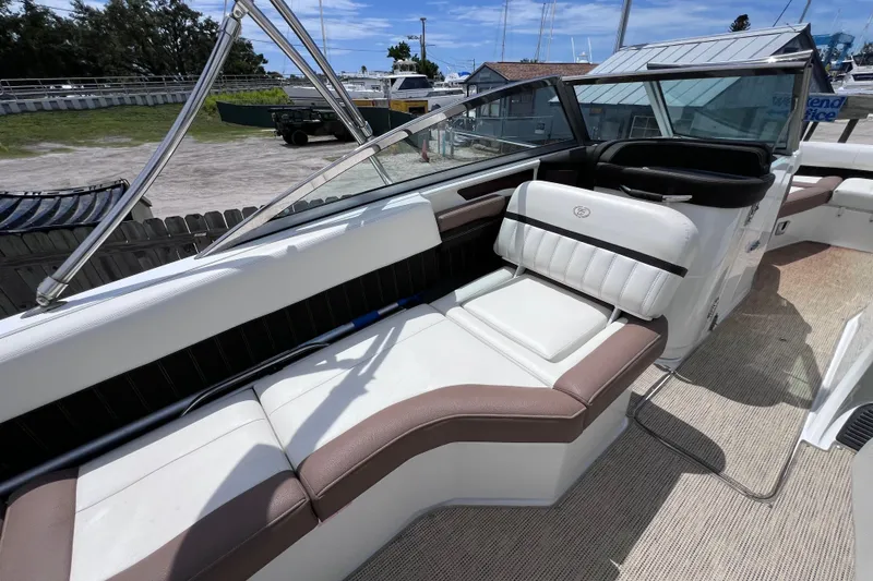 Slide: The Image of 2015 Cobalt 26SD boat interior with white and brown seating, docked outdoors. - 23