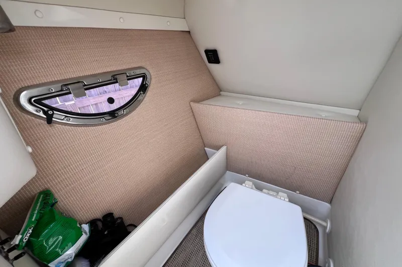 Slide: The Image of 2015 Cobalt 26SD boat interior with compact bathroom and window. - 26