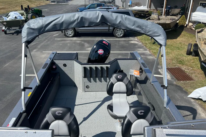 Slide: The Image of 2025 Crestliner 1850 Commander boat interior with seating and motor, parked outdoors. - 10