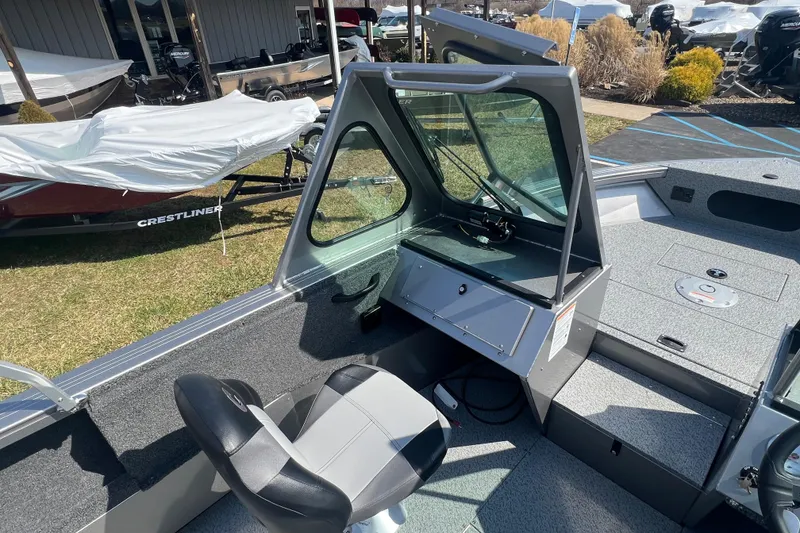 Slide: The Image of 2025 Crestliner 1850 Commander boat interior with helm and seating, displayed outdoors. - 12