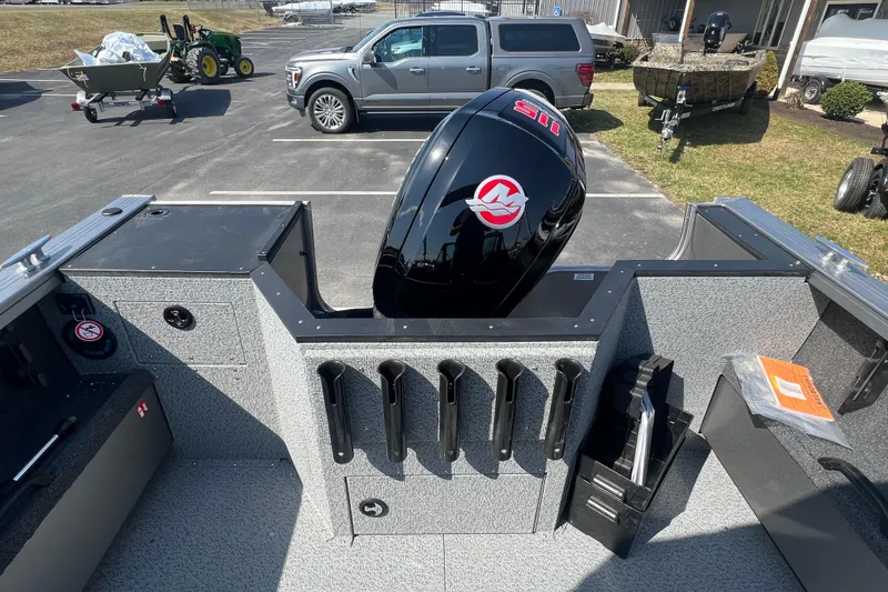 Slide: The Image of 2025 Crestliner 1850 Commander boat interior with motor, parked near vehicles and equipment. - 16