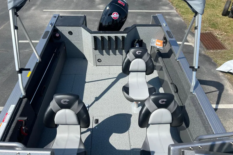 Slide: The Image of 2025 Crestliner 1850 Commander boat interior with seating and motor, parked on pavement. - 9